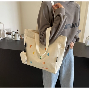 Close-up of cream canvas tote bag with colorful letters and matching mini coin purse