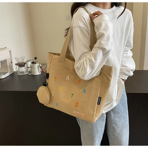 Close-up of khaki canvas tote bag with colorful letter embroidery and detachable pouch