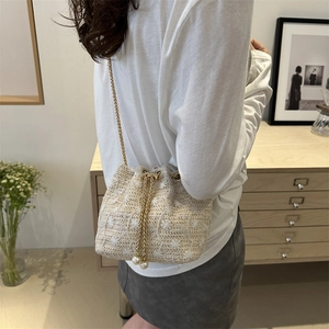 Minimalist beige woven bucket bag with white floral embroidery and gold chain strap