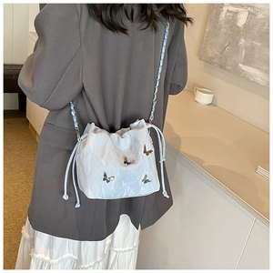 Detalle del bolso de cubo azul claro con textura plisada y detalles de mariposas de metal