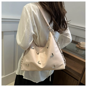 Close-up of beige butterfly hobo bag with silver metallic charms and chain strap detail