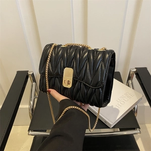 Détail du sac en cuir matelassé noir avec bandoulière chaîne dorée et fermoir pivotant