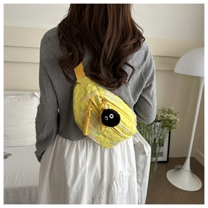 Detailed view of yellow textured crossbody bag with colorful stitching and fuzzy charm