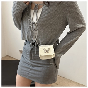 Detail of a white mini shoulder bag featuring a decorative silver butterfly bow buckle