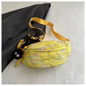 Detail of yellow crossbody bag with stripe embroidery and black plush sprite charm