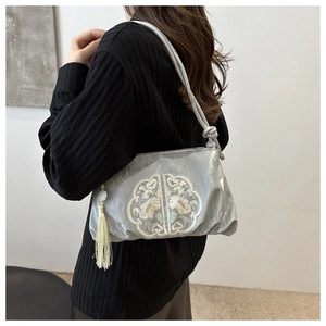 Détail de broderie de nuages et fleurs sur un sac en satin gris de style chinois avec gland