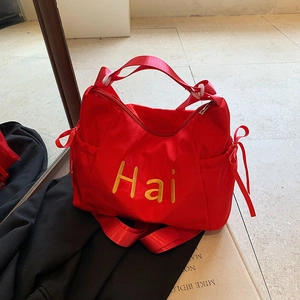 Detailed view of red nylon tote bag featuring yellow embroidery and side bow drawstring