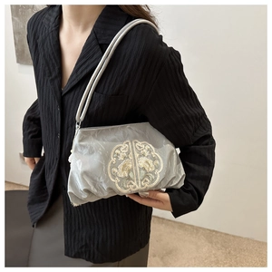 Détail d'un sac en satin argenté avec broderie florale chinoise et plis délicats