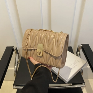 Détail du sac à bandoulière matelassé beige avec chaîne dorée et texture à motifs ondulés