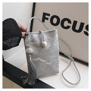 Detail of silver marble crossbody bag with pearl clasp and lotus tassel pendant