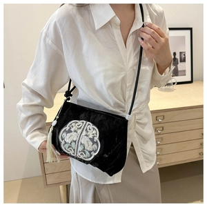 Detail of black velvet crossbody bag with traditional Chinese floral embroidery and white tassel