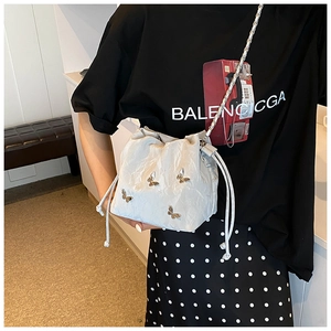 Detalle de bolso saco plateado con adornos de mariposa metálicos y correa de cadena
