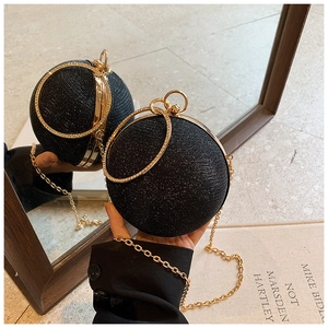 Detail of spherical evening bag with black glitter texture and gold metal ring handle