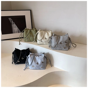 Detalle de bolsos bombonera de colores con textura arrugada y adornos de mariposa metálica