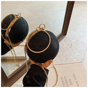 Detail of black spherical evening bag with glitter fabric, gold chain, and crystal handle