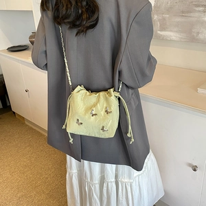 Bolso saco verde claro con colgantes de mariposa plateados y correa de cadena
