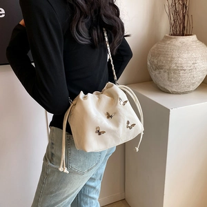 Bolso de cubo minimalista en cuero blanco con dijes de mariposa dorada en modelo
