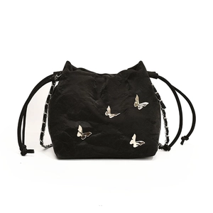 Bolso saco negro minimalista con dijes de mariposa plateados y correa de cadena