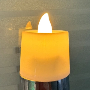 Realistic LED pillar candle with warm yellow glow and silver metallic base for party decor