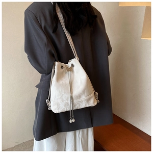 Detail of white marble-patterned bucket bag with golden butterfly charm and pearl chain