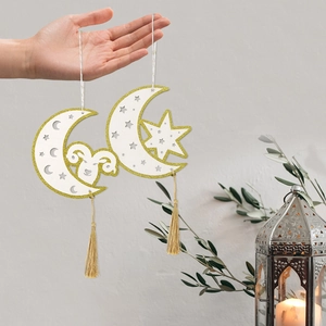 Two gold-trimmed Eid moon wooden ornaments with tassels and festive star patterns
