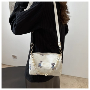 Détail du sac bandoulière en tissu blanc avec ours imprimés et chaîne en perles chic