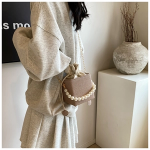 Detail of woven brown handbag featuring a pearl handle and secure drawstring closure