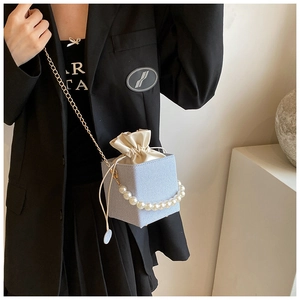 Close-up of mini blue striped box bag with pearl handle and satin drawstring lining