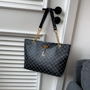 Deep blue tote bag with clover pattern, gold hardware and deer charm on white door