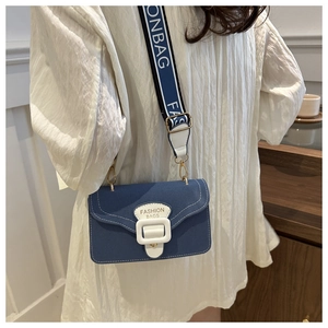 Detail der blauen quadratischen Tasche mit weißem breitem Gurt und Modeschriftzug