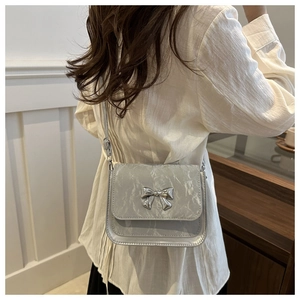 Detail of silver crossbody bag with metallic bow and textured crinkle finish