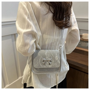 Close-up of a silver bow buckle on a wrinkled texture metallic crossbody handbag