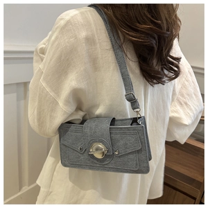 Sac bandoulière en feutre gris avec boucle ronde en métal et rivets porté par un mannequin