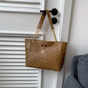 Brown tote bag with geometric floral print and gold reindeer pendant for women