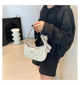 Vue détaillée d'un sac à bandoulière tissé blanc avec broderie florale et gros nœud