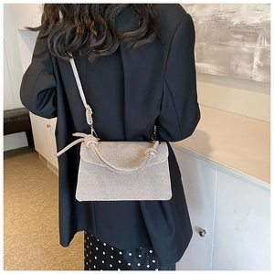 Chic beige textured crossbody bag with unique knot handle shown on casual outfit