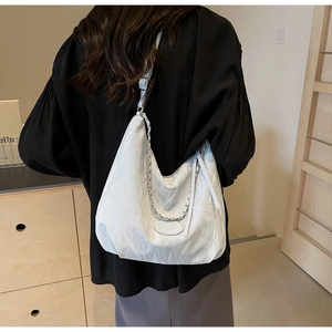 Detail of white wrinkled PU leather hobo bag with silver chain strap and metal buckle