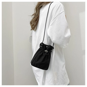 Detail of minimalist black drawstring bucket bag showing silver eyelets and sleek shoulder strap