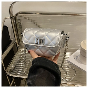 Close-up of silver quilted saddle bag featuring metallic gloss and chain strap detail