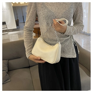 Detail of white leather crescent shoulder bag with silver chain and minimalist texture