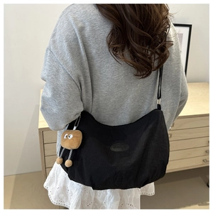 Detail of black nylon crossbody bag with fashion patch and plush toast pendant