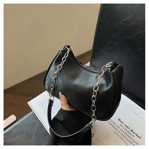 Detail of black underarm bag with plant texture, silver chain and leather handle