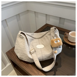 Detail of beige tote bag with pleated texture, fashion logo patch and cute plush charm