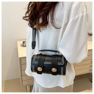 Détail du sac cylindrique noir avec rivets métalliques et bandoulière ethnique vintage