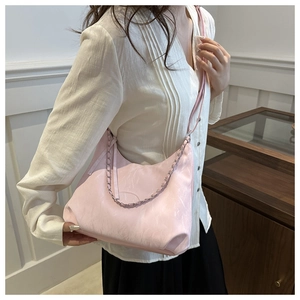 Borsa rosa a mezzaluna con catena argentata indossata su un abbigliamento bianco