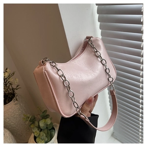 Pink hobo bag with silver chain strap shown in a stylish minimalist setting