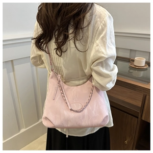 Vista dettagliata di una borsa a tracolla rosa a mezzaluna con catena su una modella