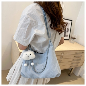 Borsa tote a pieghe azzurra con catena in metallo e charm a nuvola su una modella