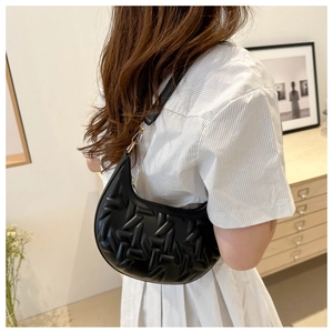 Detail of black crescent hobo bag with 3D woven texture and golden metal buckle