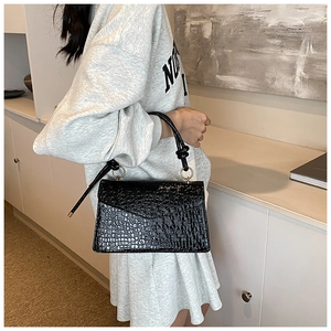 Detail of black stone pattern handbag with knotted handle and golden ring hardware